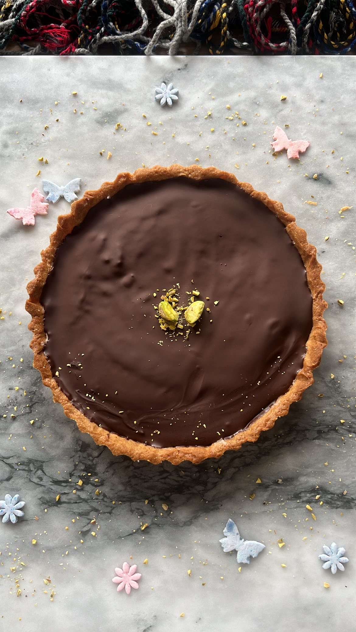 A large chocolate tart decorated with pistachios on top