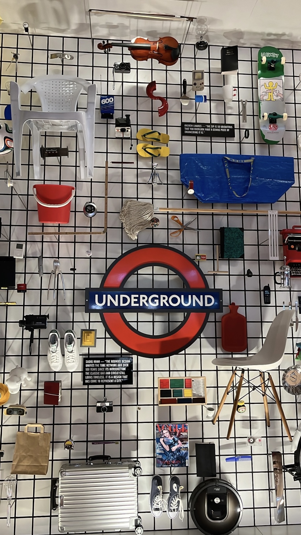 A wall at the Design Museum displaying an eclectic mix of everyday products, including shoes, chairs, mops, and more, showcasing the intersection of design and functionality.