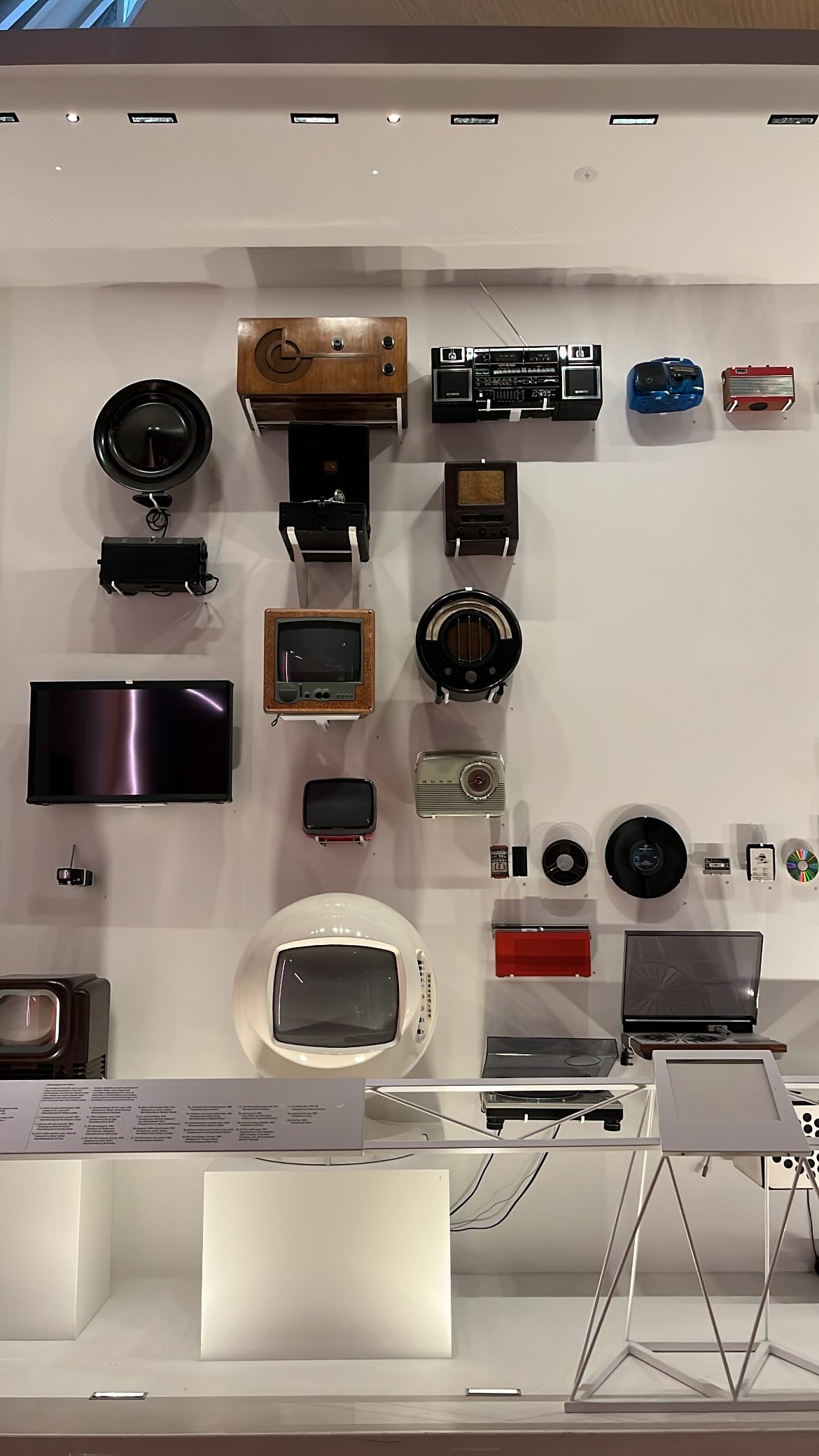 A wall display of vintage technology at the Design Museum, featuring retro TVs and radios that showcase the evolution of media design.