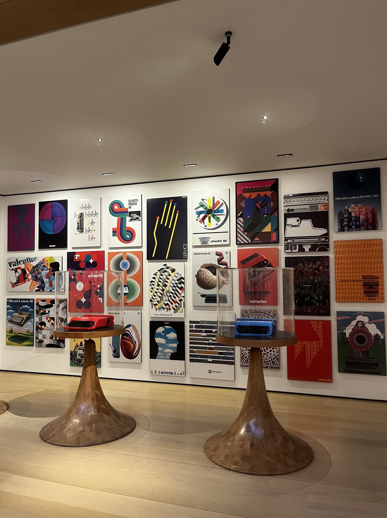 A vibrant wall covered in colorful posters at the Design Museum, showcasing diverse graphic designs and artistic expressions in a bold, eye-catching display.