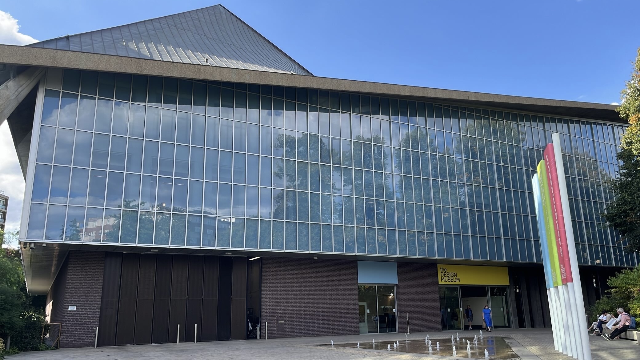 The modern exterior of the Design Museum in London, with its sleek, geometric architecture and expansive glass windows.