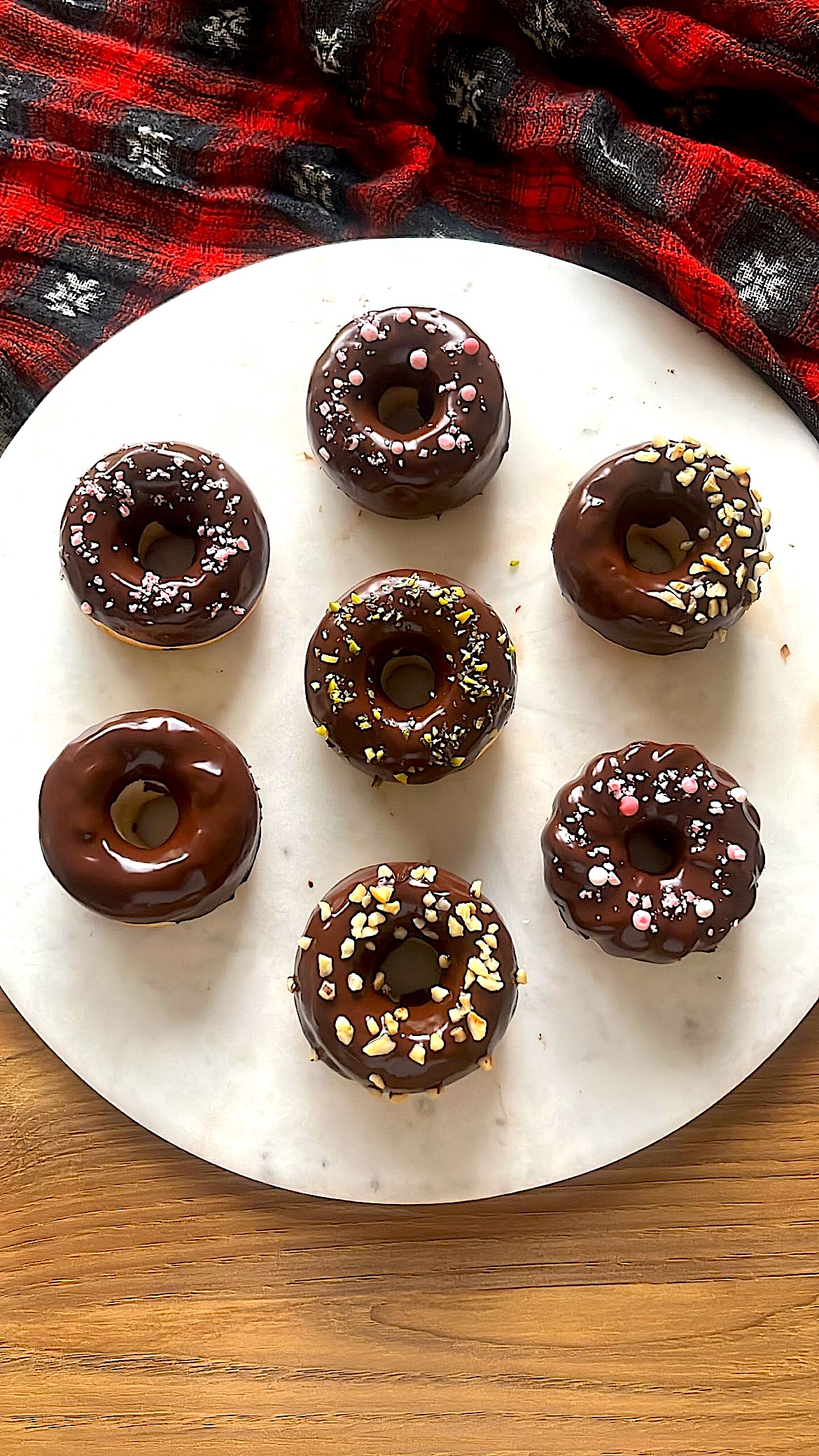 Donuts dipped in chocolate and nuts create different patterns with a shiny appearance