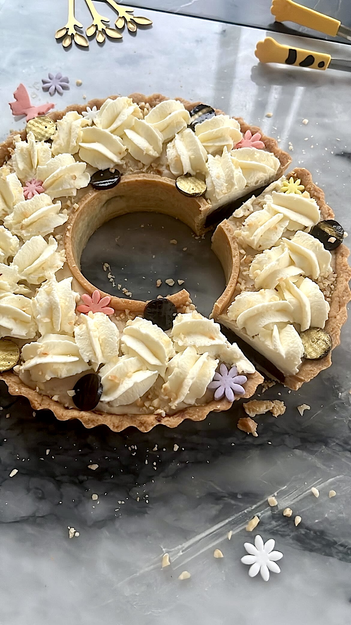 Tart ring topped with heart-shaped cream, decorated with flower-shaped sugar toppers and choco pieces.