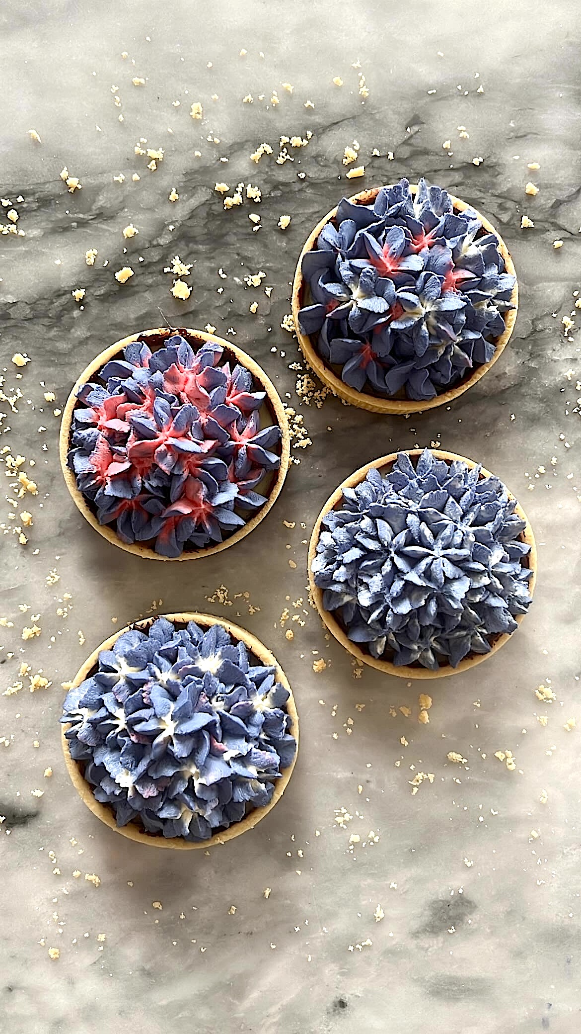 Tart topped with hydrangea-shaped cream decoration in a mix of red and violet colors