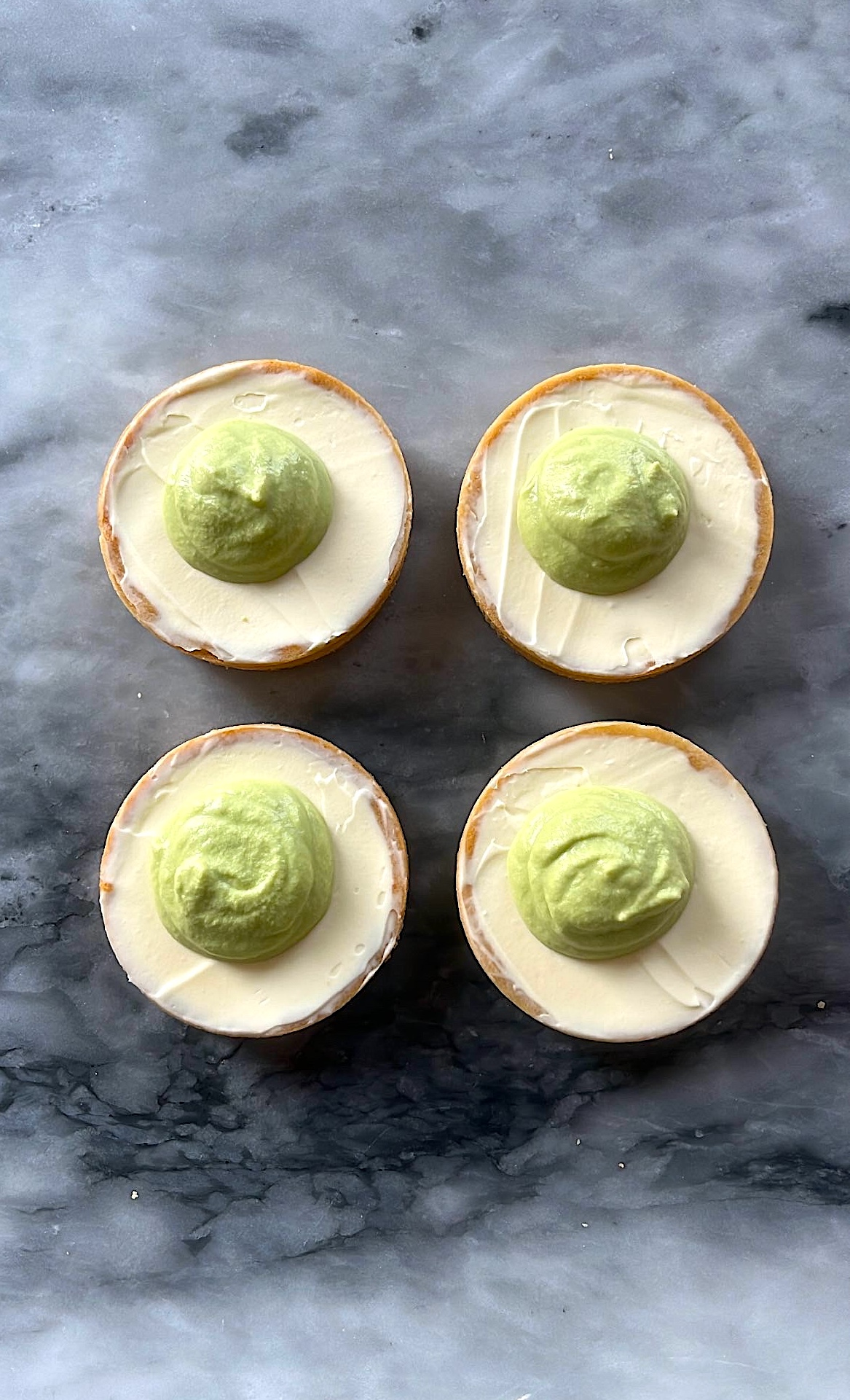 Tarts with cream added on top, with small semi-sphere in the center.