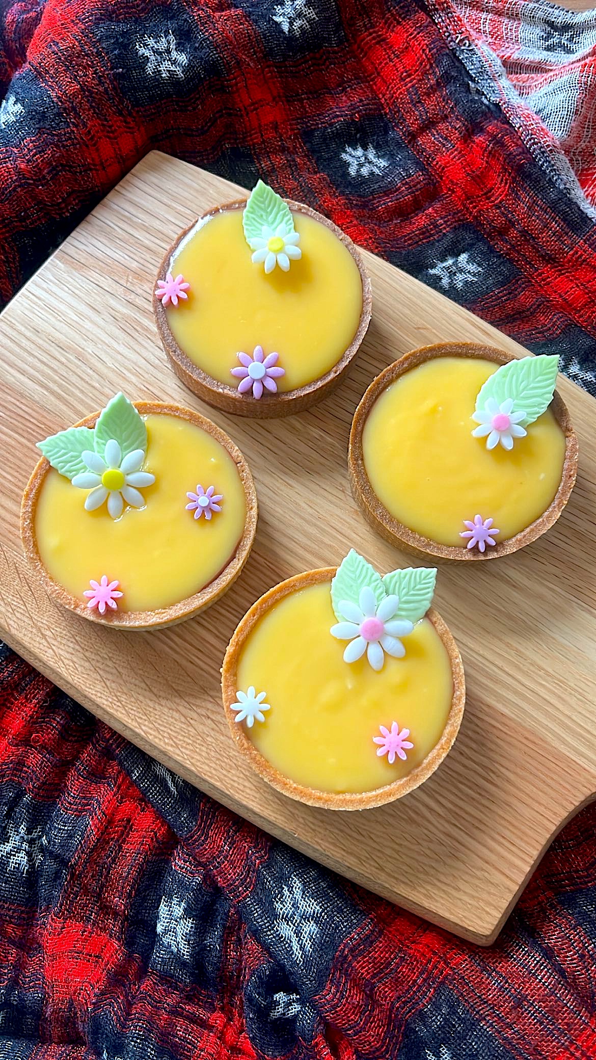 Four lemon tarts decorated with flower-shaped sugar toppings