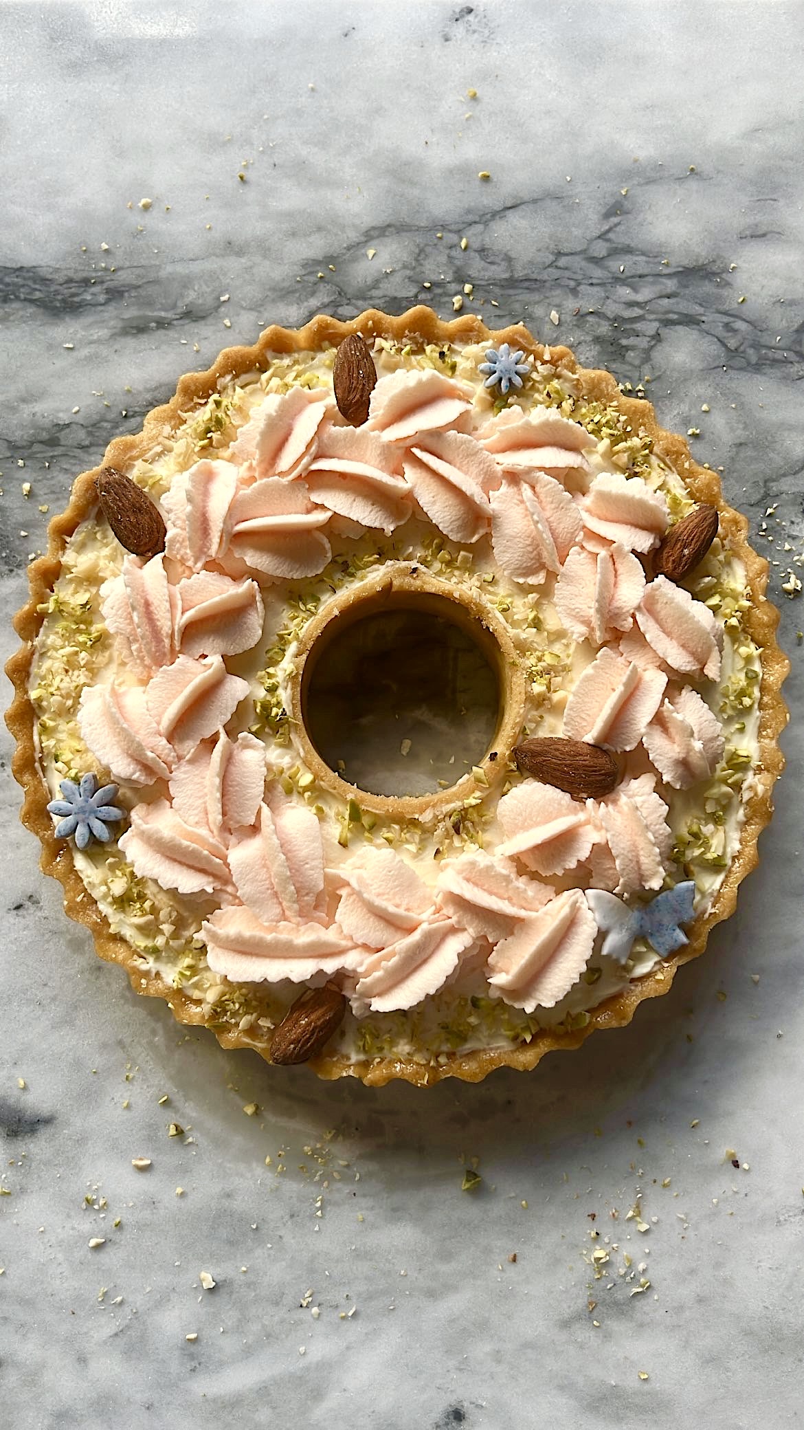 Tart ring topped with pink heart-shaped cream, decorated with almonds.