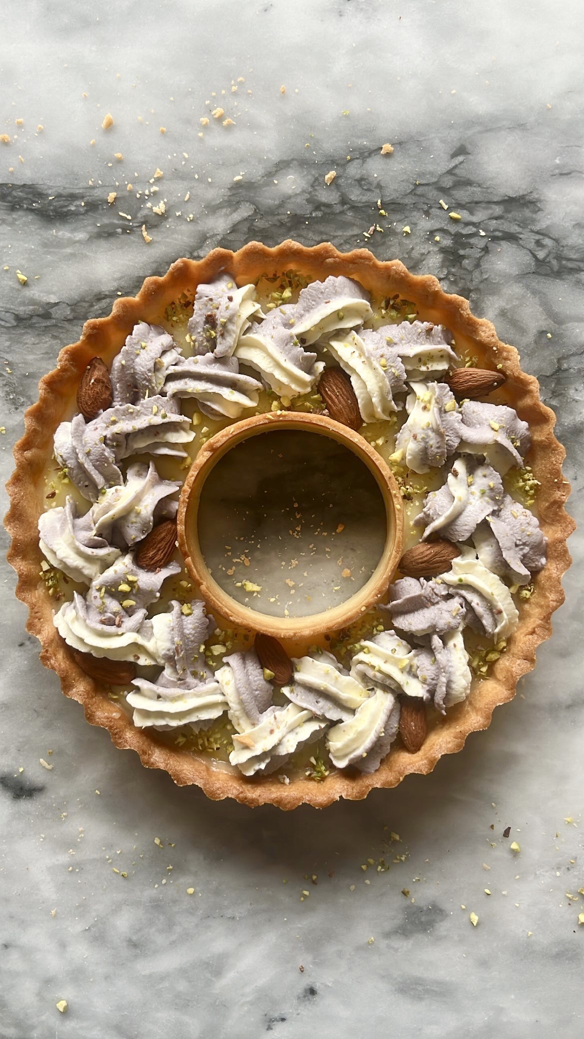 Tart ring topped with purple and white heart-shaped cream, decorated with almonds.