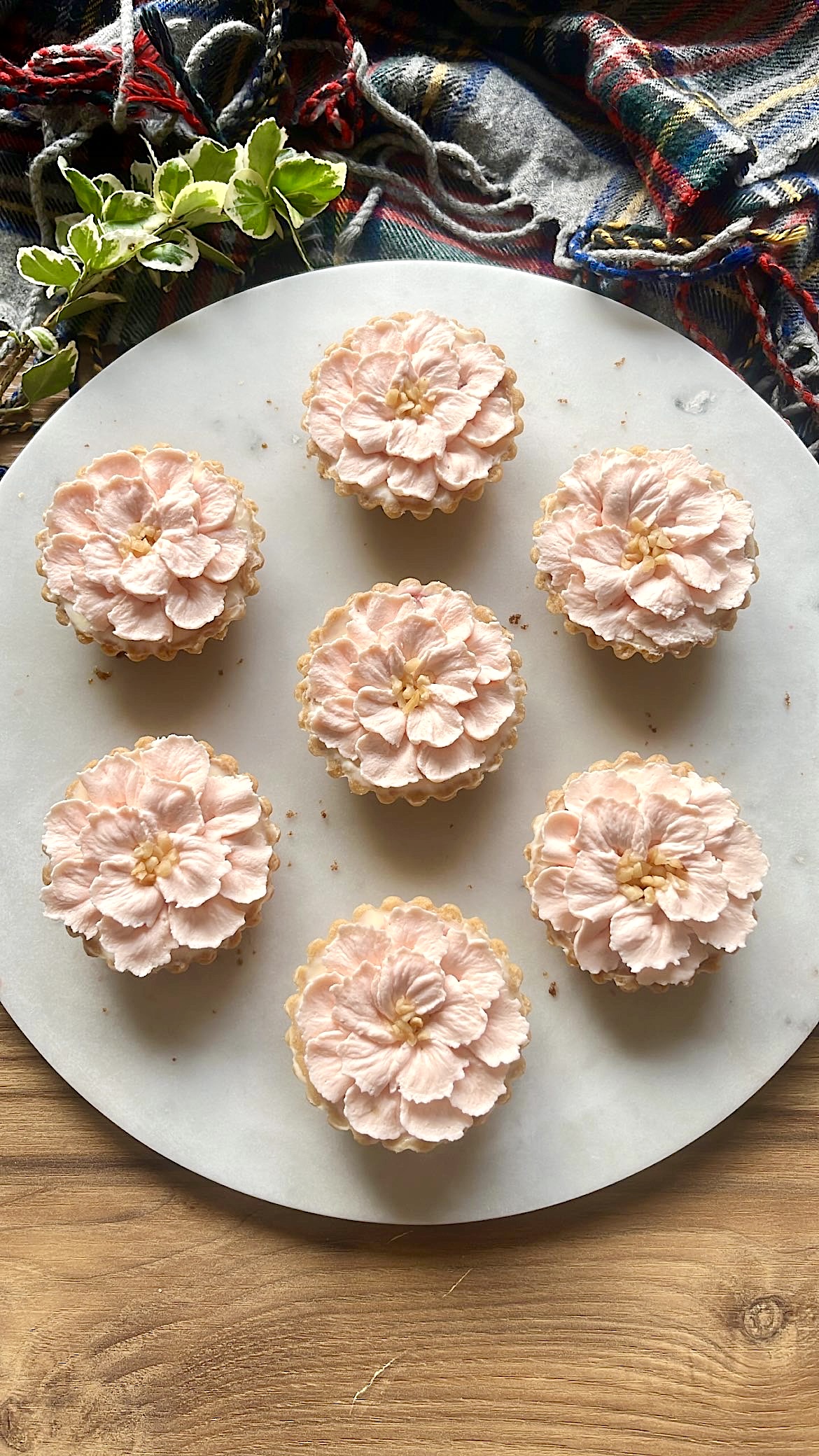 Seven small tarts decorated with pink flower-shaped cream piping on top