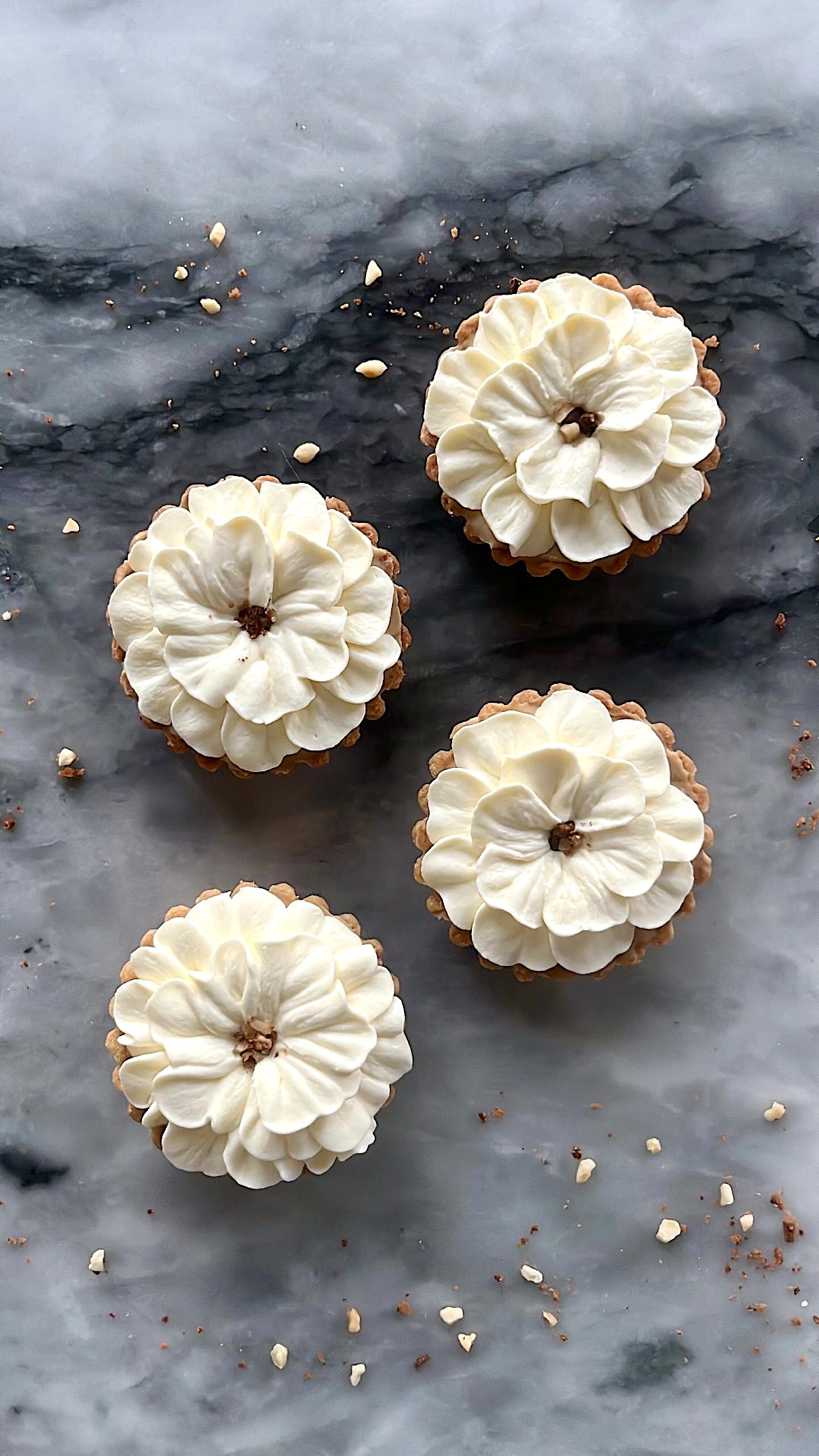 Four small tarts decorated with flower-shaped cream piping on top