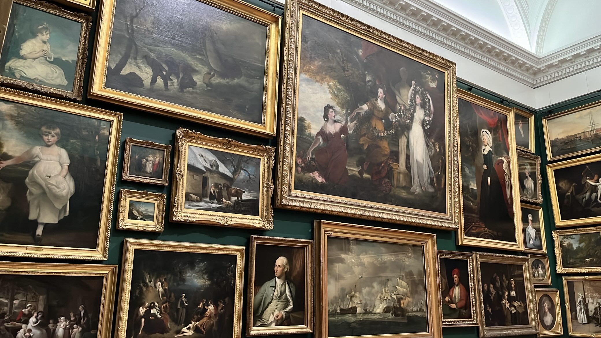 Wall adorned with a diverse collection of paintings in Tate Britain, showcasing various styles and artists that invite exploration and appreciation.