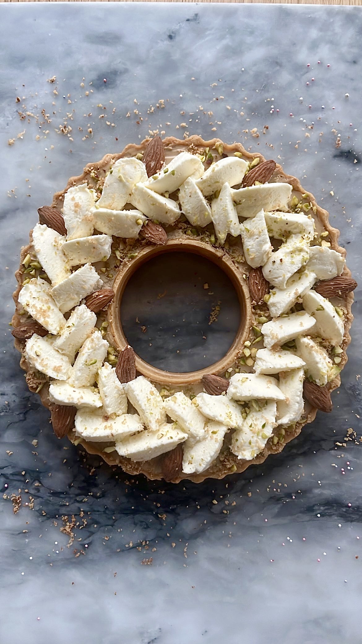 Tart ring topped with thick heart-shaped cream, decorated with almonds.